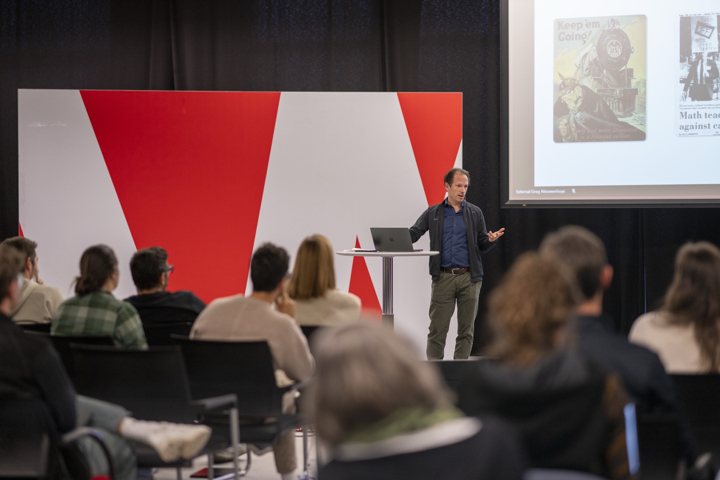 Greg Nieuwenhuys on stage presenting to an audience